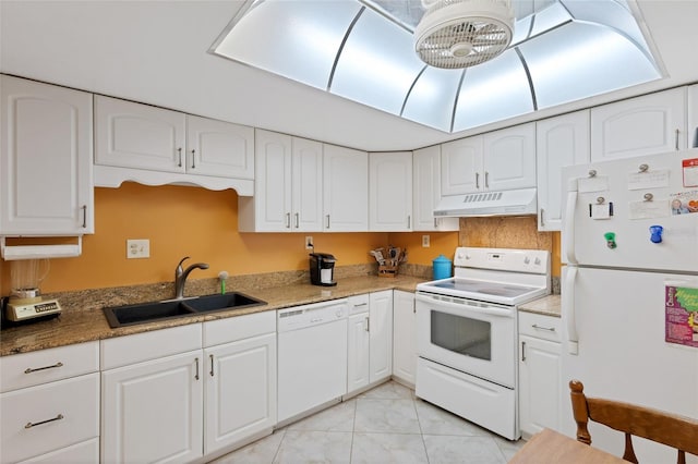 kitchen with light tile floors, dark stone counters, white appliances, white cabinets, and sink