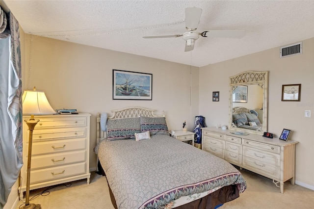 bedroom with light carpet, ceiling fan, and a textured ceiling