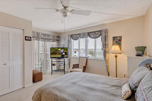 carpeted bedroom with a closet, a textured ceiling, and ceiling fan