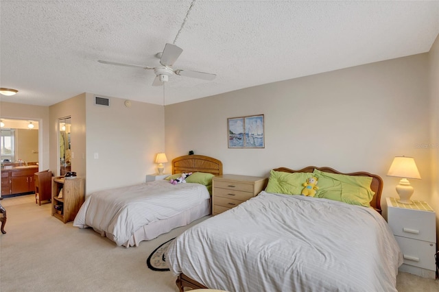 bedroom featuring light carpet, ensuite bath, ceiling fan, and a textured ceiling