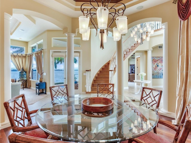 dining room featuring ornate columns, an inviting chandelier, and light hardwood / wood-style floors