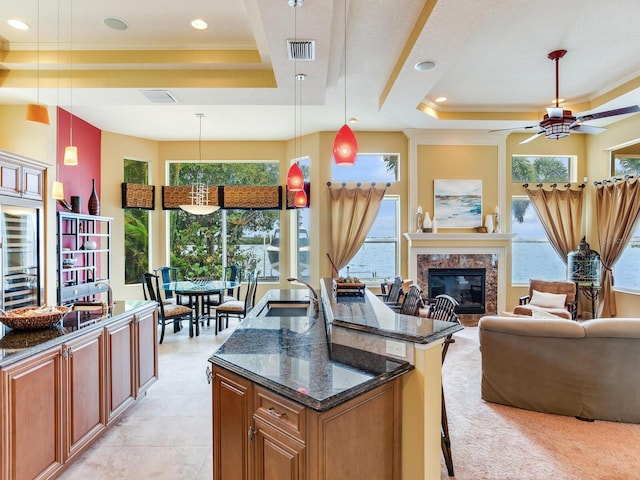 kitchen with a raised ceiling, a kitchen breakfast bar, pendant lighting, and dark stone counters