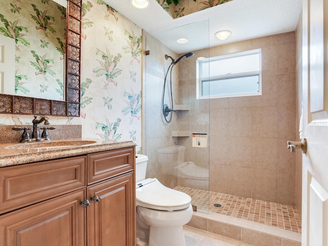 bathroom featuring toilet, a tile shower, and vanity