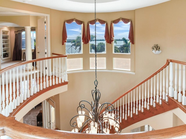 stairway featuring decorative columns and a notable chandelier