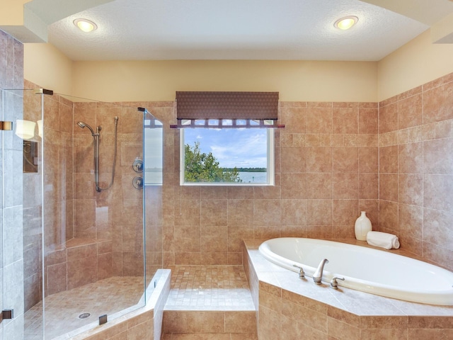 bathroom featuring a textured ceiling and shower with separate bathtub