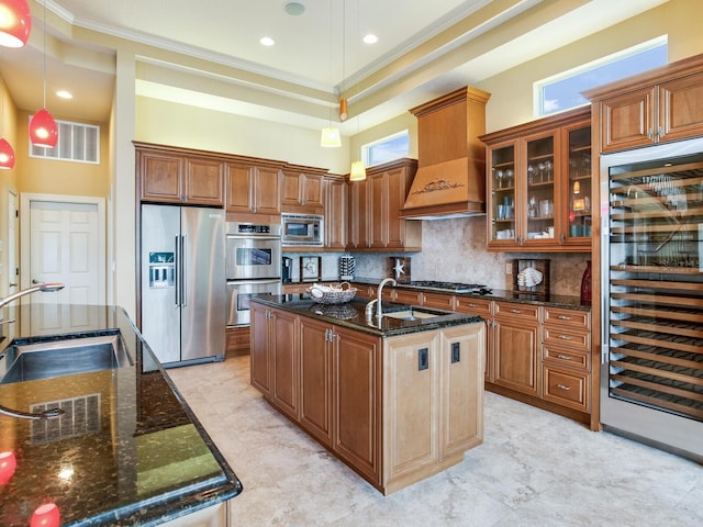 kitchen featuring beverage cooler, appliances with stainless steel finishes, hanging light fixtures, an island with sink, and sink