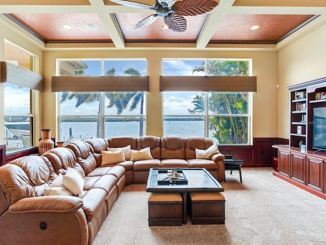 carpeted living room with a wealth of natural light, wooden walls, coffered ceiling, and a water view