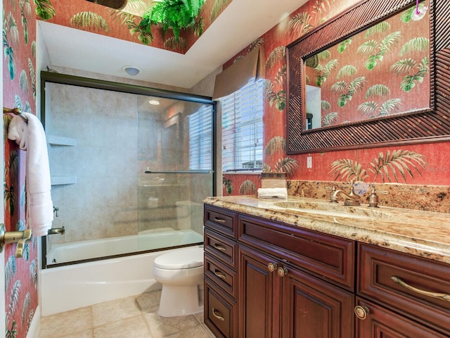 full bathroom featuring toilet, tile patterned flooring, vanity, and combined bath / shower with glass door