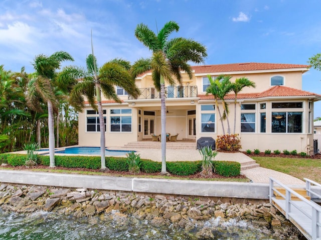 rear view of property with a balcony, a water view, and a patio