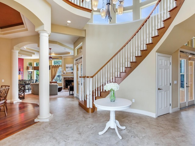 entrance foyer featuring hardwood / wood-style flooring, a chandelier, a high ceiling, a premium fireplace, and decorative columns