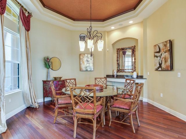 dining space with hardwood / wood-style floors, ornamental molding, a tray ceiling, and a notable chandelier