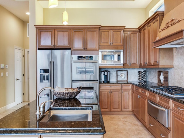 kitchen with custom exhaust hood, decorative backsplash, dark stone counters, appliances with stainless steel finishes, and sink