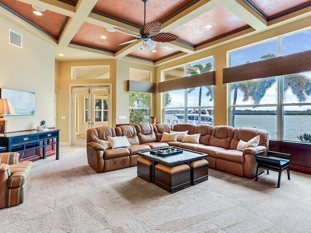 carpeted living room featuring a water view, coffered ceiling, a high ceiling, crown molding, and beam ceiling