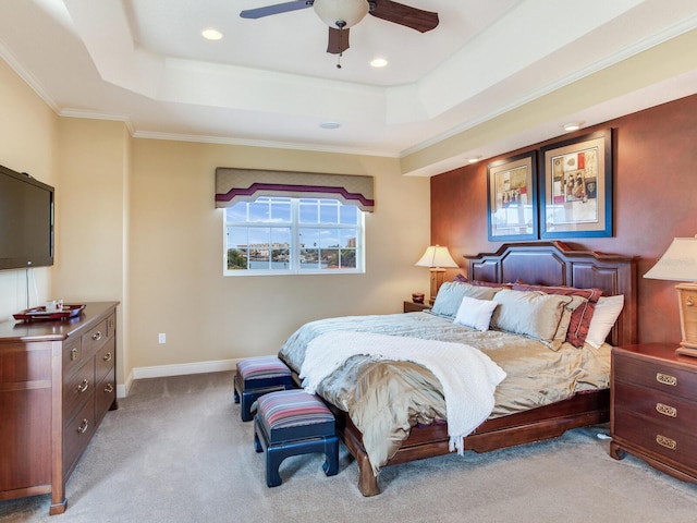 bedroom with ceiling fan, light colored carpet, crown molding, and a tray ceiling