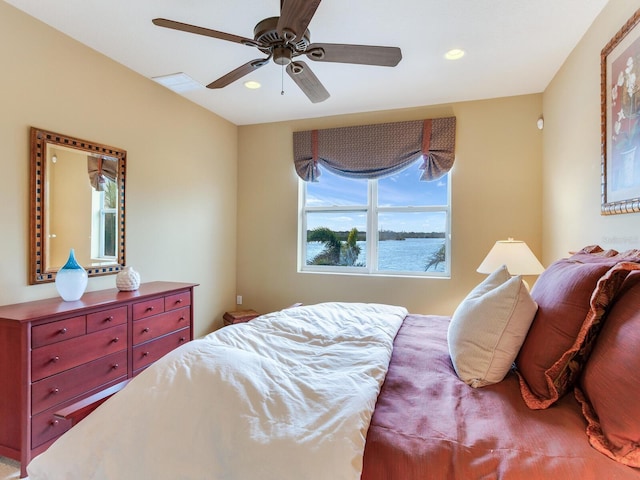 bedroom featuring multiple windows, ceiling fan, and a water view