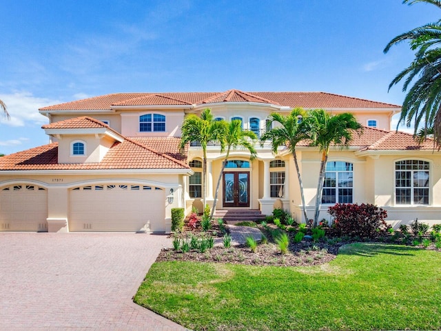 mediterranean / spanish home featuring french doors, a front yard, and a garage