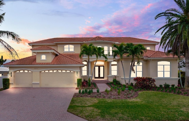 mediterranean / spanish-style house with a lawn, french doors, and a garage