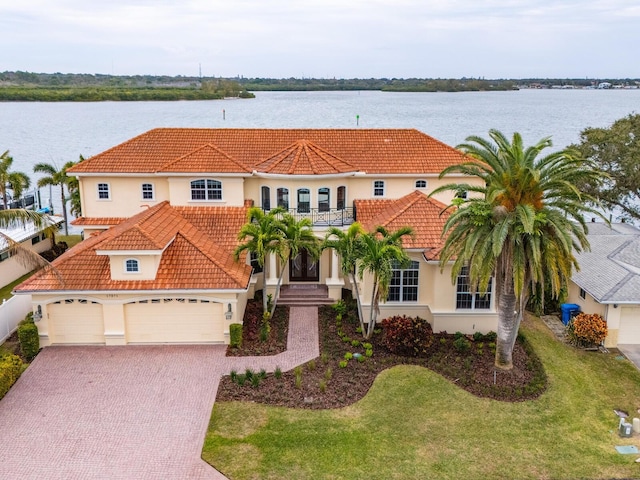 mediterranean / spanish-style home with a balcony, a garage, a water view, and a front lawn