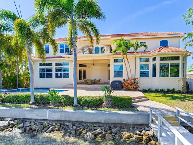 rear view of property with french doors, a balcony, ceiling fan, and a patio