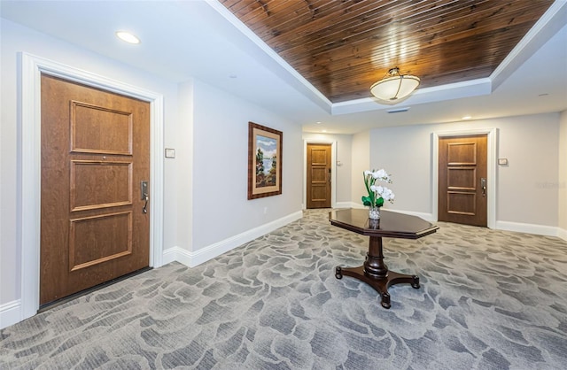 interior space featuring dark colored carpet, wooden ceiling, and a tray ceiling