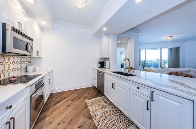 kitchen featuring light stone countertops, backsplash, sink, light wood-type flooring, and stainless steel appliances