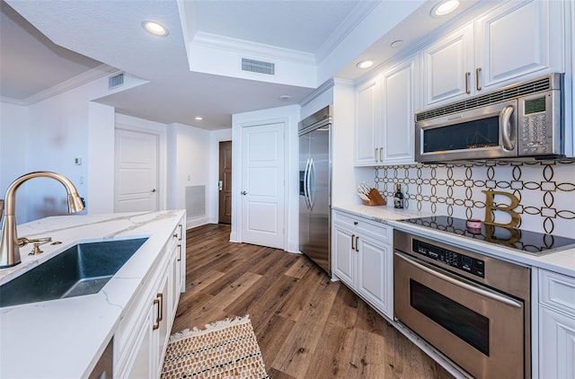 kitchen with dark hardwood / wood-style floors, sink, ornamental molding, stainless steel appliances, and white cabinetry