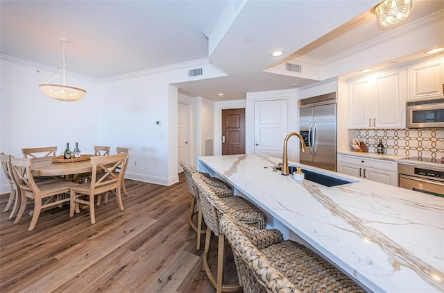 kitchen featuring light stone countertops, white cabinetry, backsplash, appliances with stainless steel finishes, and sink