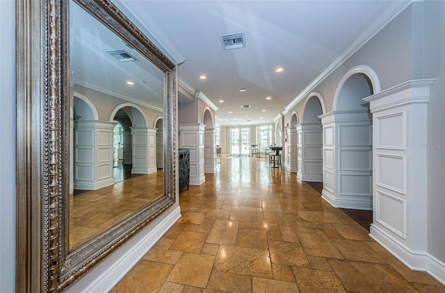 hall featuring tile flooring, ornate columns, and ornamental molding