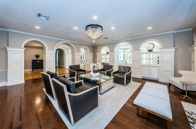 living room featuring an inviting chandelier, decorative columns, ornamental molding, and dark hardwood / wood-style flooring