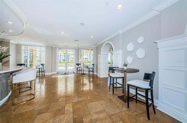 living area with tile flooring, decorative columns, french doors, and crown molding