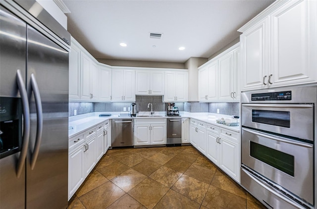 kitchen featuring backsplash, dark tile floors, appliances with stainless steel finishes, and white cabinetry