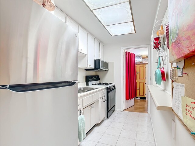 kitchen with light tile patterned floors, black range with gas stovetop, stainless steel fridge, and white cabinets