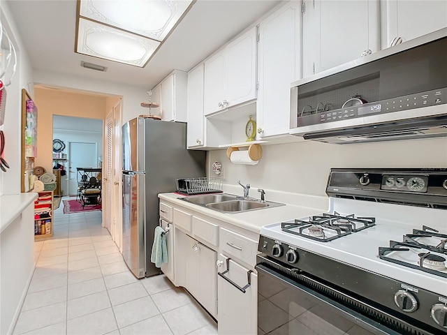 kitchen featuring white cabinetry, appliances with stainless steel finishes, sink, and light tile patterned floors