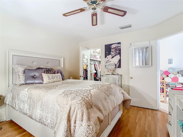 bedroom featuring ceiling fan, a spacious closet, a closet, and light hardwood / wood-style flooring