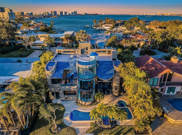 aerial view at dusk featuring a water view and a city view