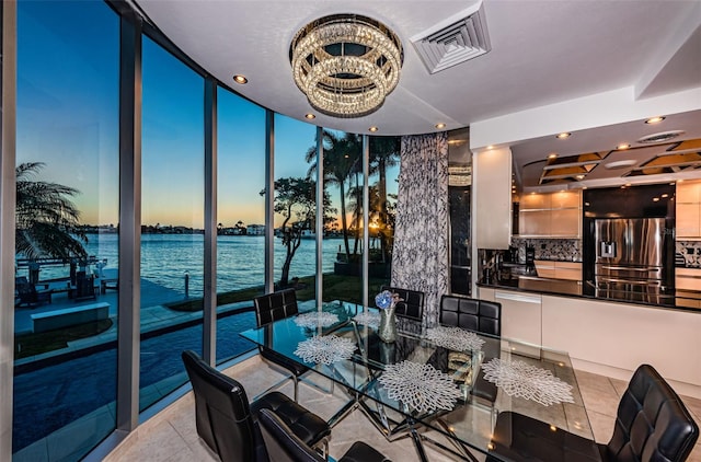 dining space with a water view, light tile floors, and a notable chandelier