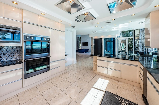 kitchen featuring light tile floors, dark stone countertops, and black appliances