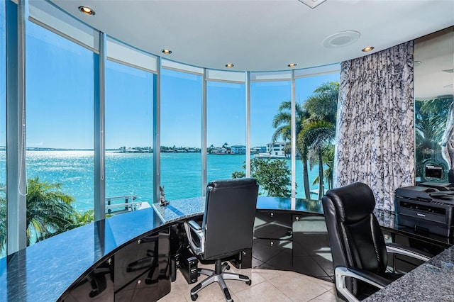 office featuring floor to ceiling windows, a water view, and light tile floors