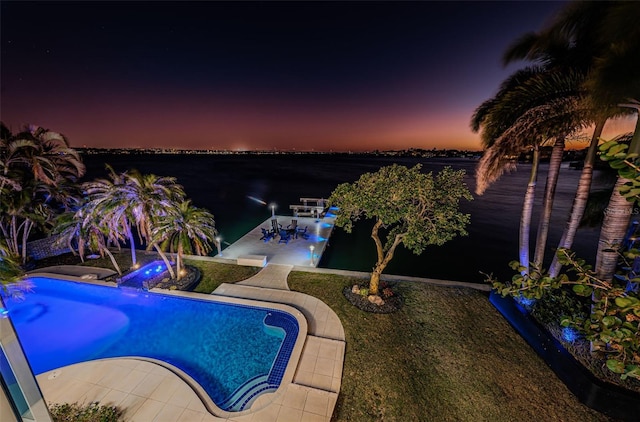 pool at dusk with a water view and a patio area