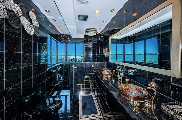 bathroom with tile walls, double vanity, toilet, and a water view