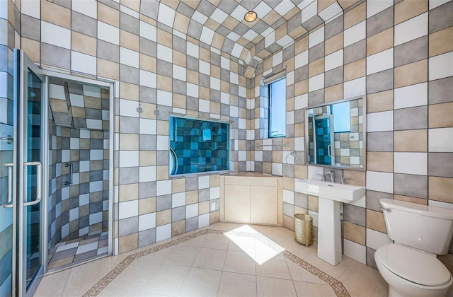 bathroom with tile walls, sink, a shower with door, tile flooring, and toilet