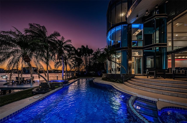 pool at dusk with a water view and a patio