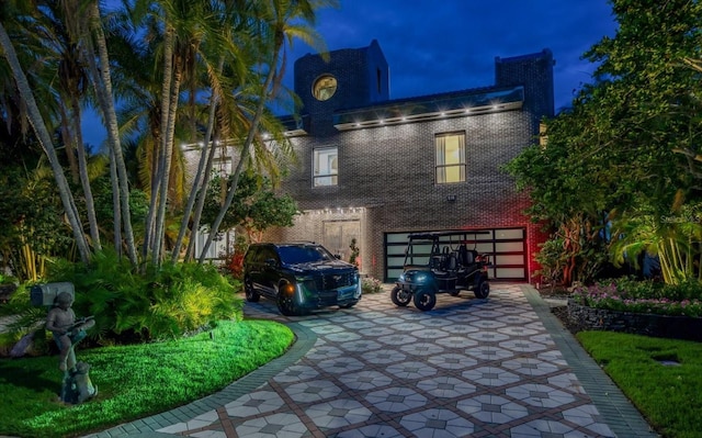 property exterior at twilight featuring an attached garage and brick siding