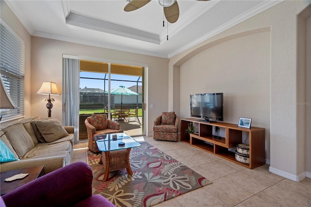 living room with crown molding, light tile floors, ceiling fan, and a tray ceiling