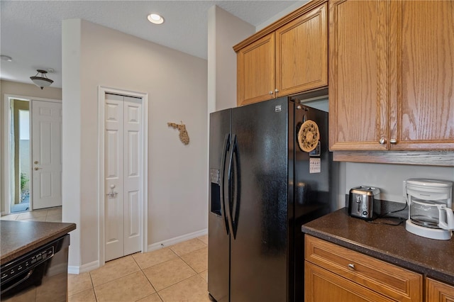 kitchen featuring light tile floors, dark stone counters, and black appliances