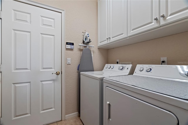 laundry area with light tile flooring, cabinets, and washing machine and clothes dryer