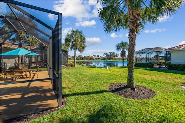 view of yard with a water view, a patio, and glass enclosure