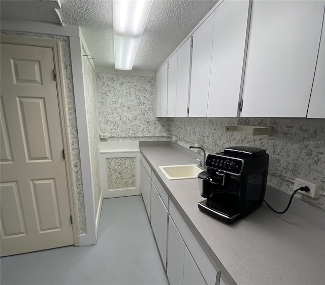 kitchen with sink, white cabinetry, and a textured ceiling