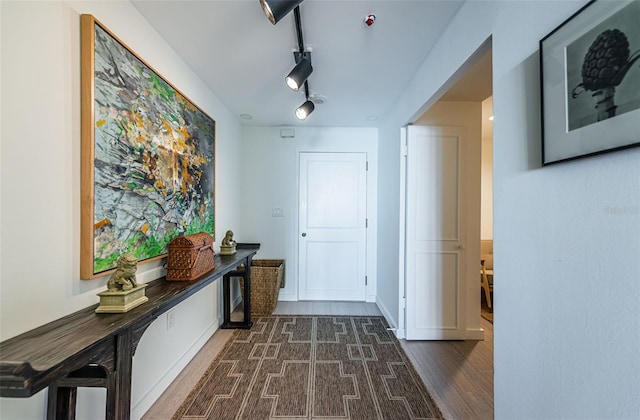 hallway with rail lighting and dark wood-type flooring