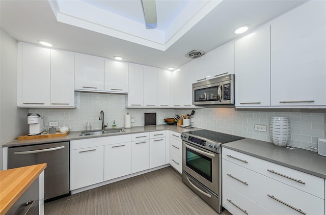 kitchen featuring backsplash, stainless steel appliances, white cabinetry, and light tile floors